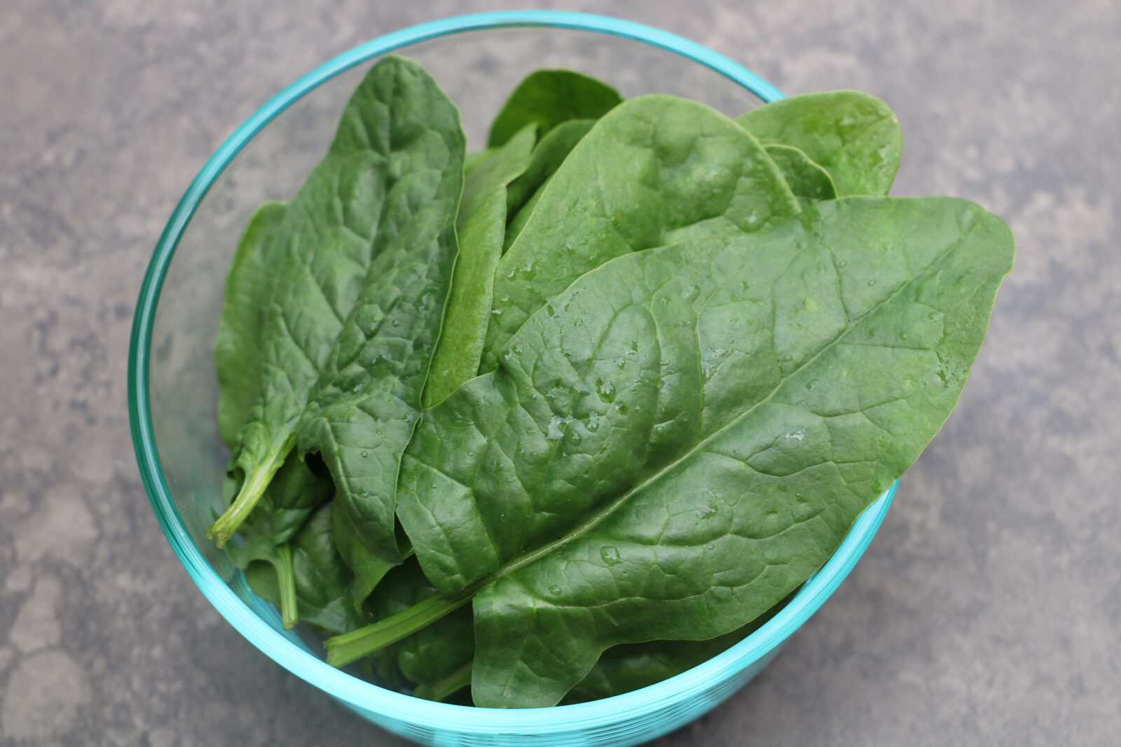 Loose green leaves of spinach in a glass bowl