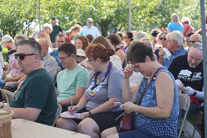 A group sits outside and many are taking notes on paper.