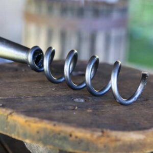 A metal corkscrew on a wooden dowel, from a corkscrew weeder on a wooden surface