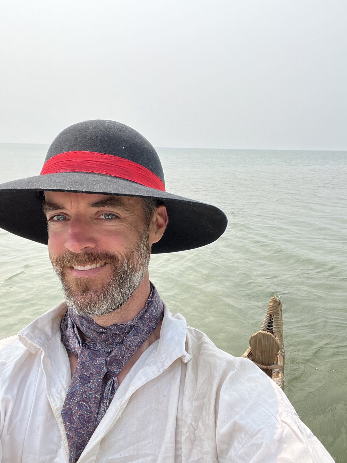 Man in a wide brimmed hat smiles to camera.