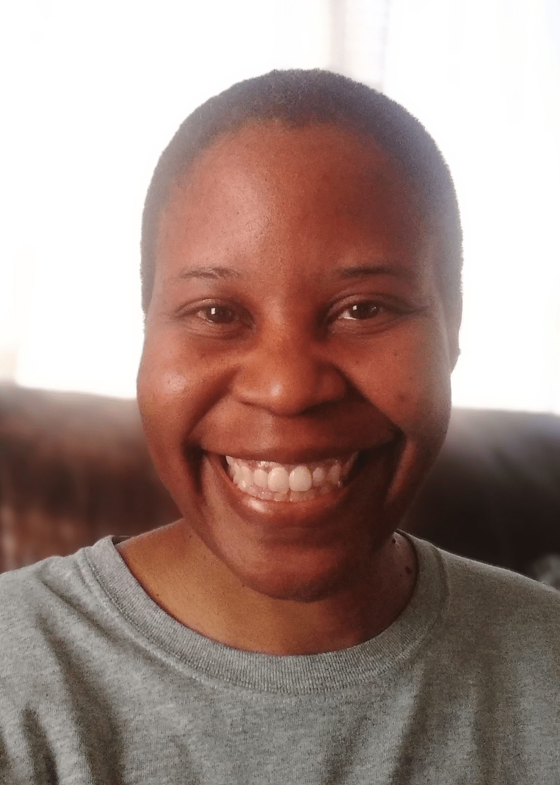 A woman in a grey t-shirt smiles to camera.