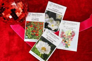 Four flower seed packets on red velvet fabric with a red disco ball and ribbon