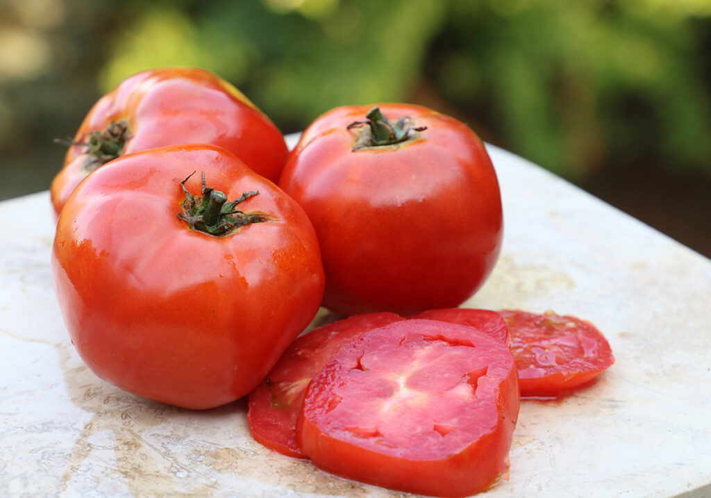 Three red 'Brandywine' tomatoes and two tomato slices