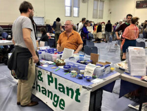 Two men talking at a table on which seeds are displayed.