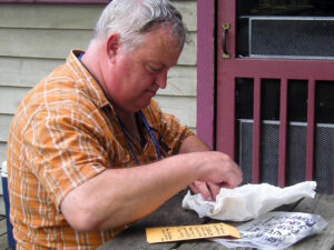 man with gray hair and orange, checkered short-sleeved shirt packing seeds.